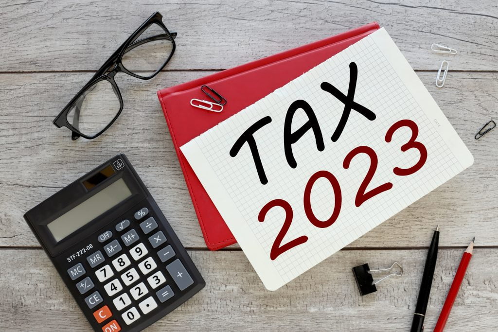April 2023/24 Tax Year notice with calculator and glasses on a table